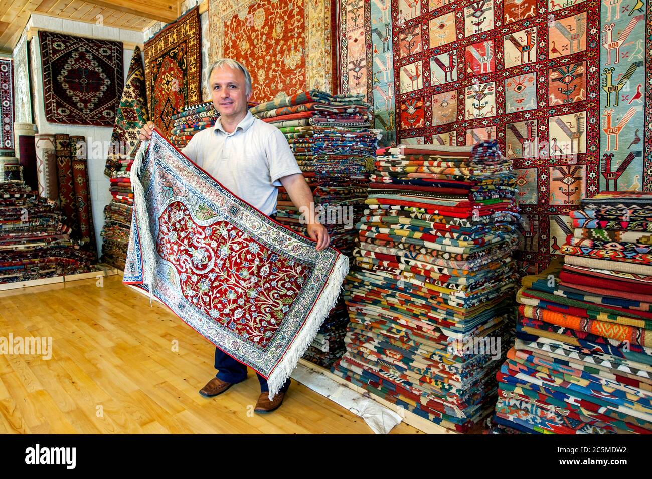 A Turkish carpet seller displays a rug in a shop in the old town of