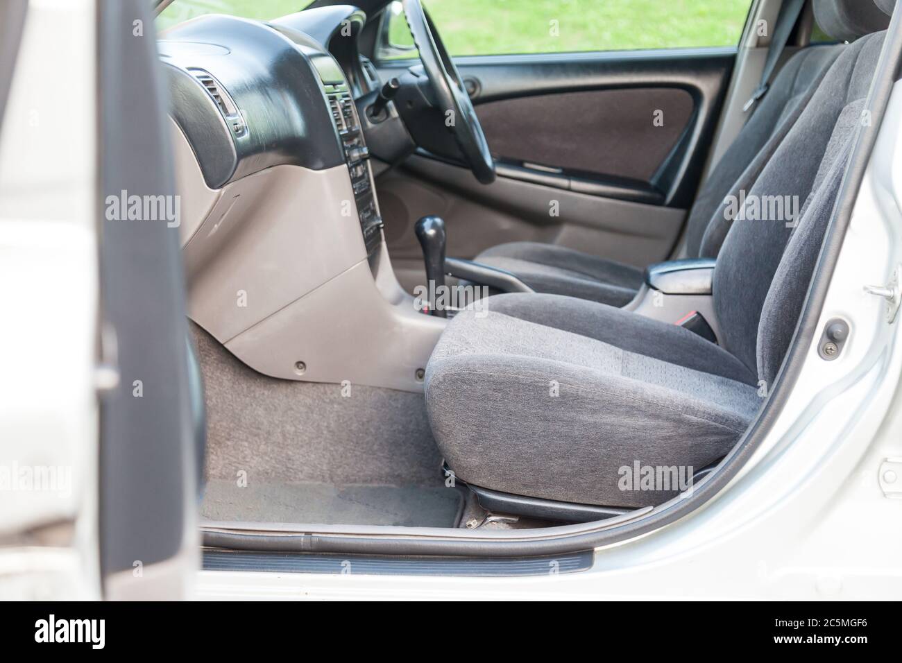 An open front passenger door of a gray sedan with seats covered in beige fabric and with a black plastic control panel, a clean interior after dry cle Stock Photo