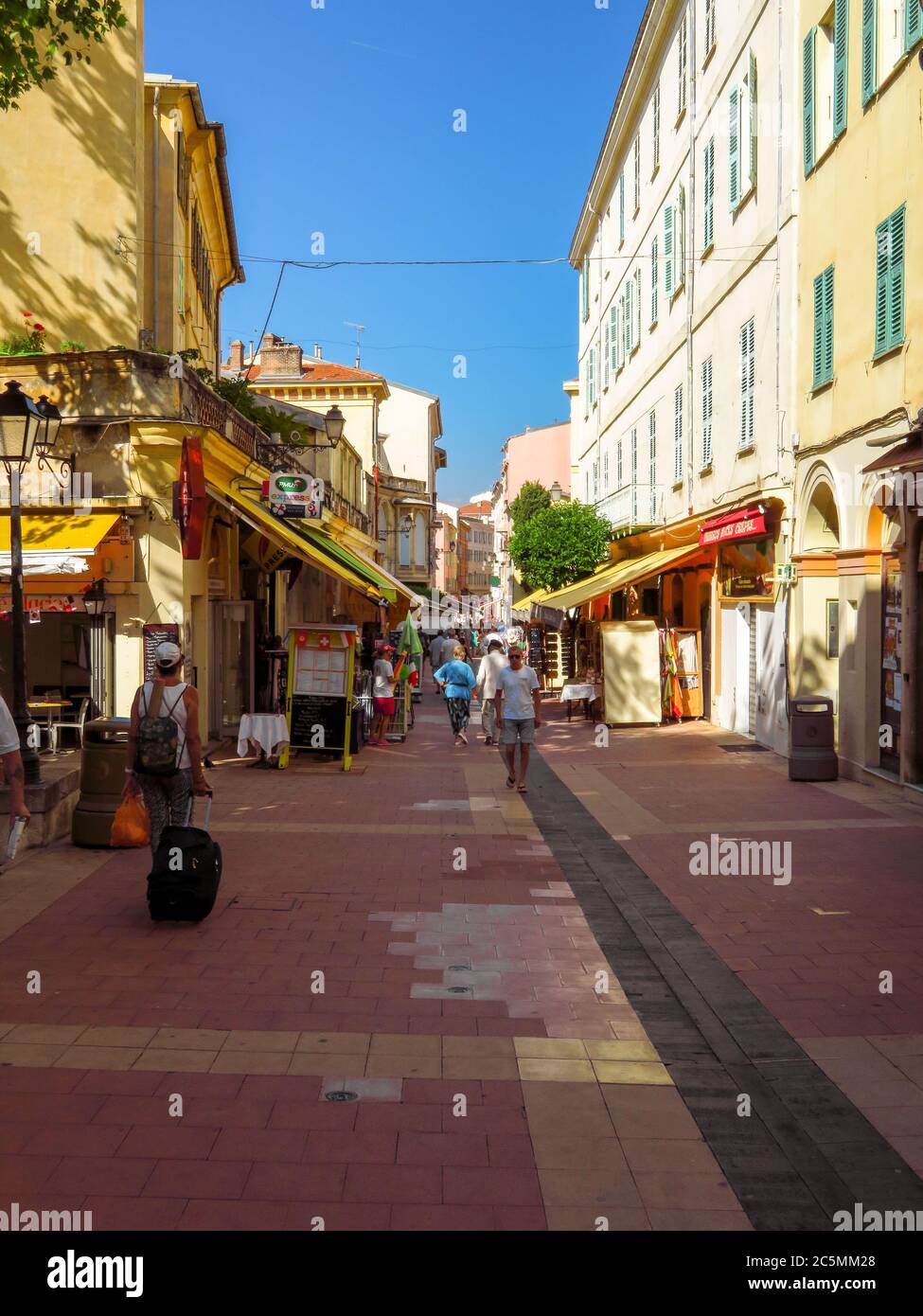 Menton, France - June 30, 2018: Small street in the old town of city. Menton is a seaside town on the French Riviera. Unidentified people walk down th Stock Photo