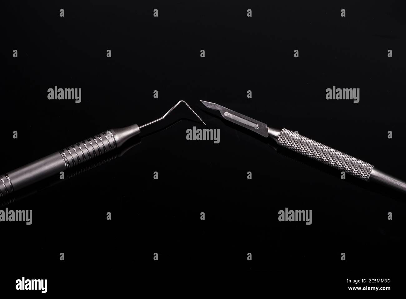 Horizontal color image with a front view of a professional dental tools on a black background. Periodontal probe and scalpel. Stock Photo