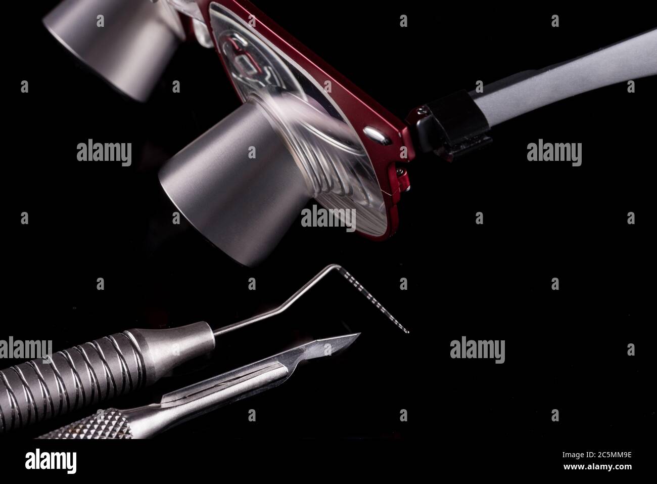 Horizontal color image with a front view of a professional dental tools on a black background Periodontal probe, scalpel and magnifying glasses. Stock Photo