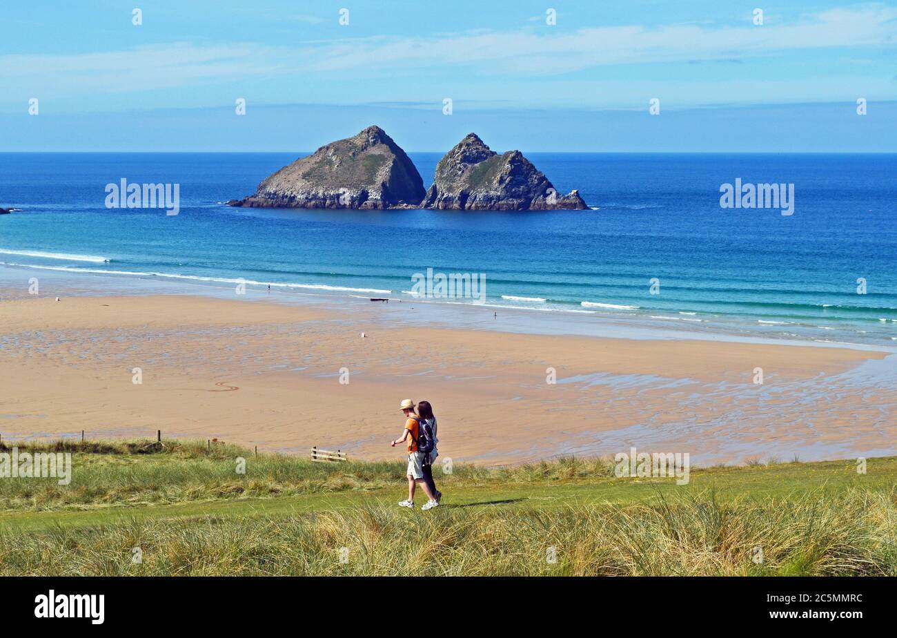 Couple walking along the coast at Hollywell Bay, Cornwall, UK Stock Photo