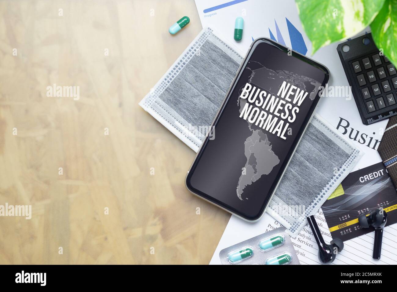 The Business New Normal After Covid-19 background concept. A smartphone with new business normal message with world map, medical face mask, medicine t Stock Photo