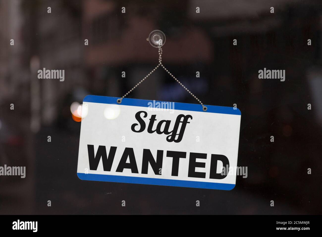 Close-up on a blue open sign in the window of a shop displaying the message: Staff wanted. Stock Photo