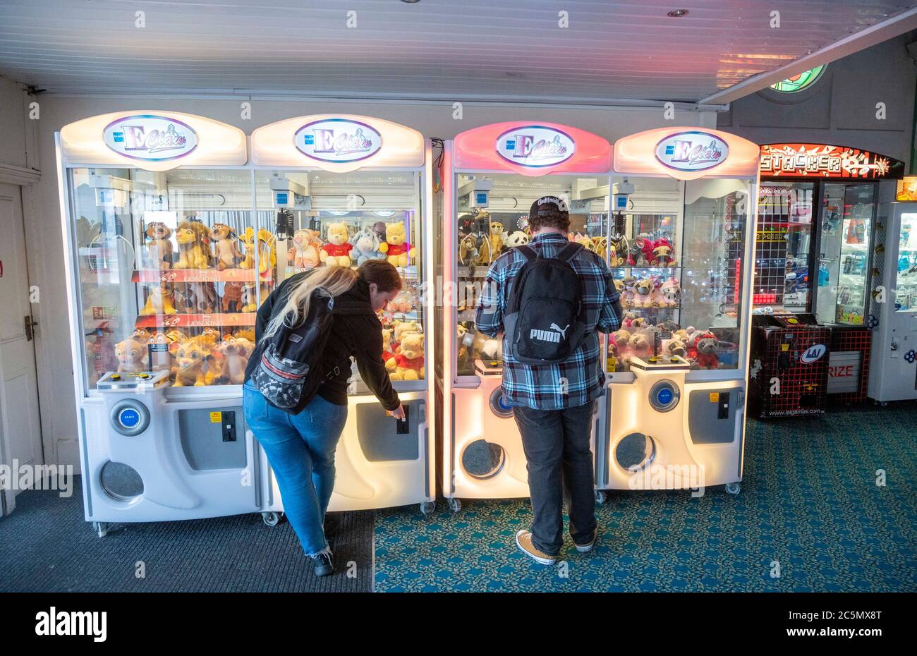 Brighton UK 4th July 2020 - The first visitors enjoy themselves  in the amusement arcade on  Brighton Palace Pier which reopened this morning as lockdown restrictions are eased further in England today with pubs , hotels and restaurants being allowed to open their doors again during the coronavirus COVID-19 pandemic crisis : Credit Simon Dack / Alamy Live News Stock Photo