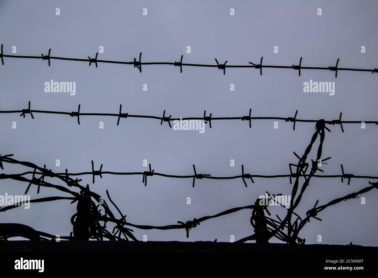 barbed wire fence on against grey sky background Stock Photo - Alamy