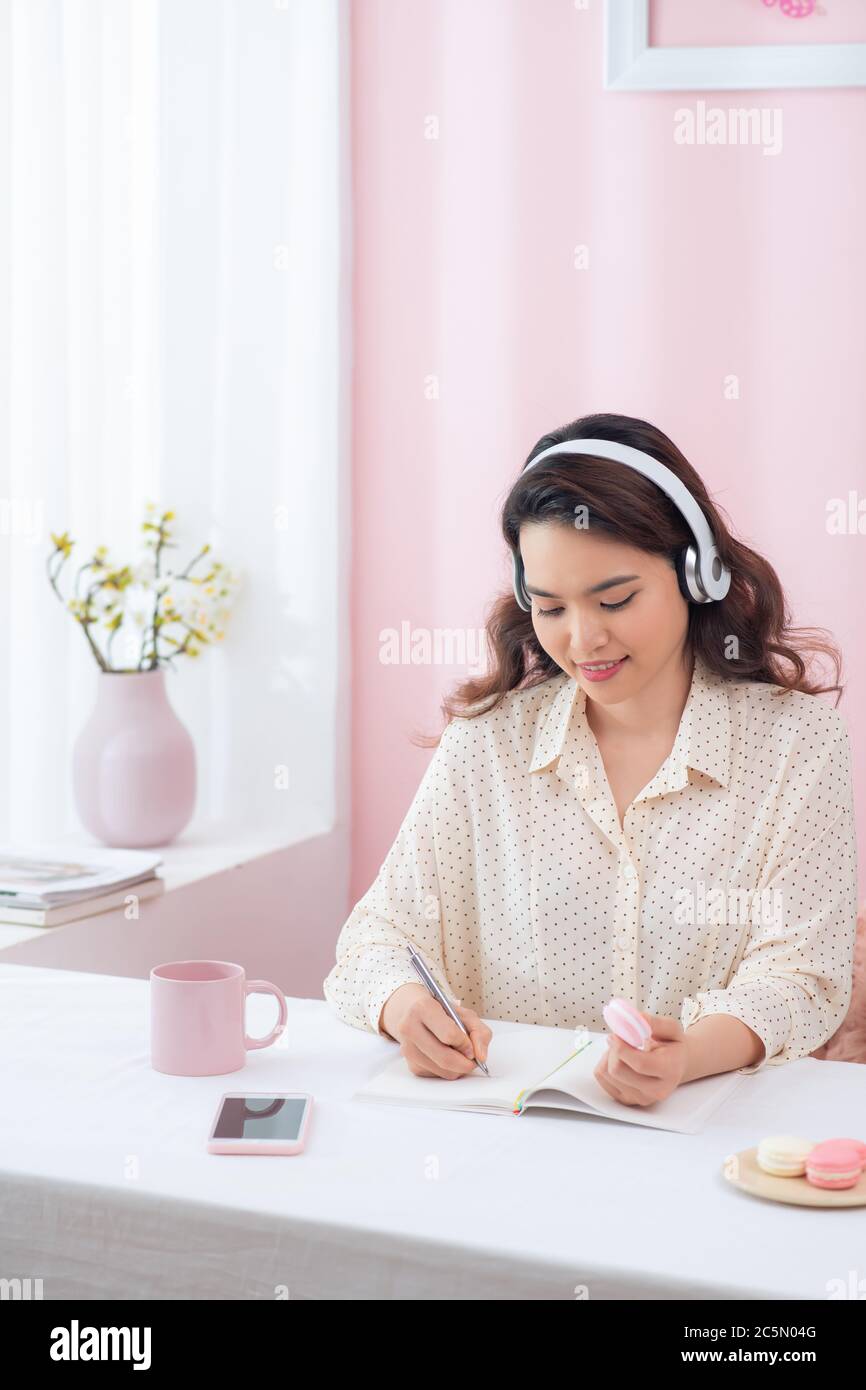 Focused woman wearing headphones write notebook Stock Photo - Alamy