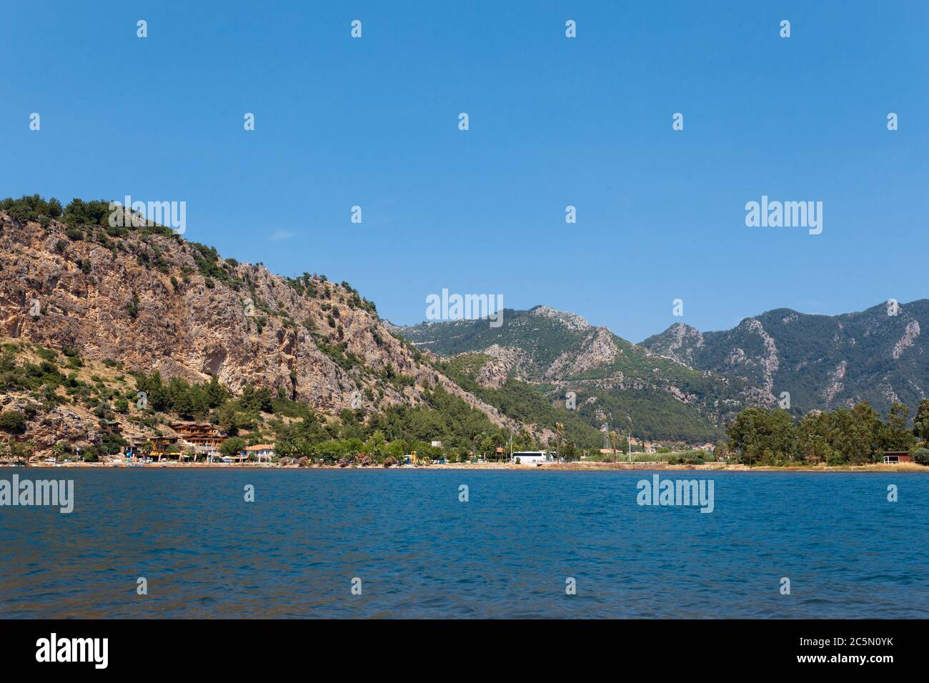 View from the sea on a tourist village on the background of a brown mountain Stock Photo