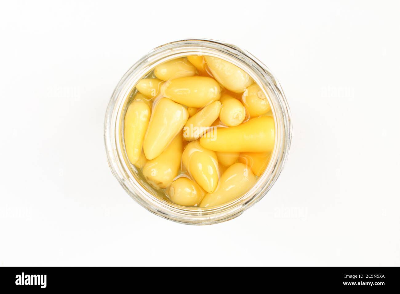 Hot yellow peppers in opened jar isolated on white surface. Top view Stock Photo