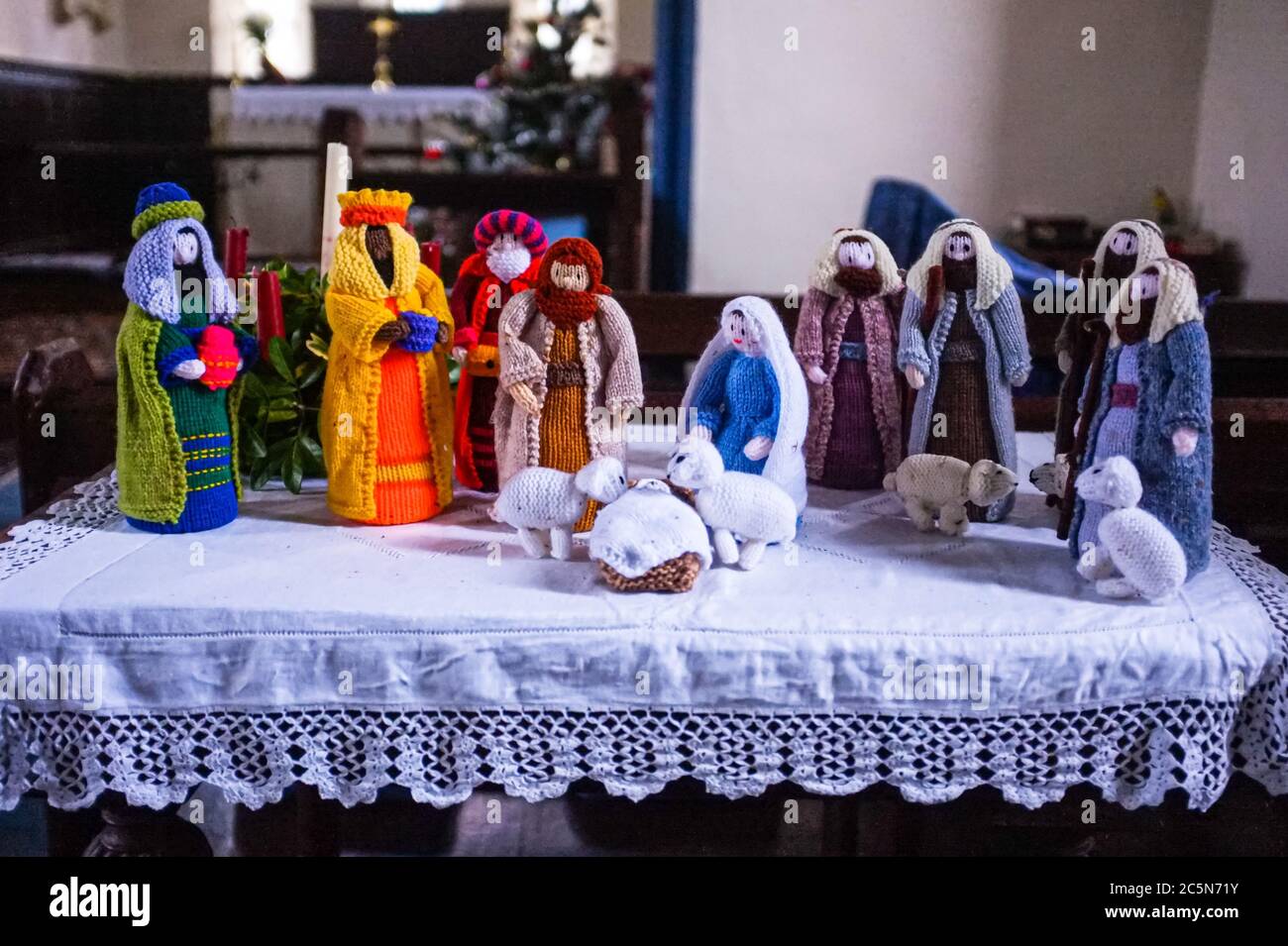 Knitted figurines depict a Christmas nativity scene on a covered table. Stock Photo