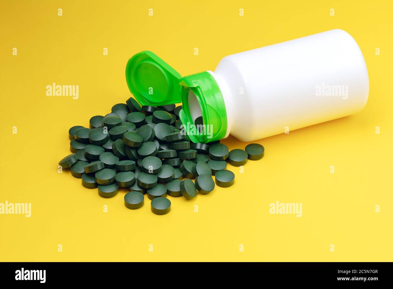 Closeup spirulina algae tablets. Chlorella tablets isolated on yellow