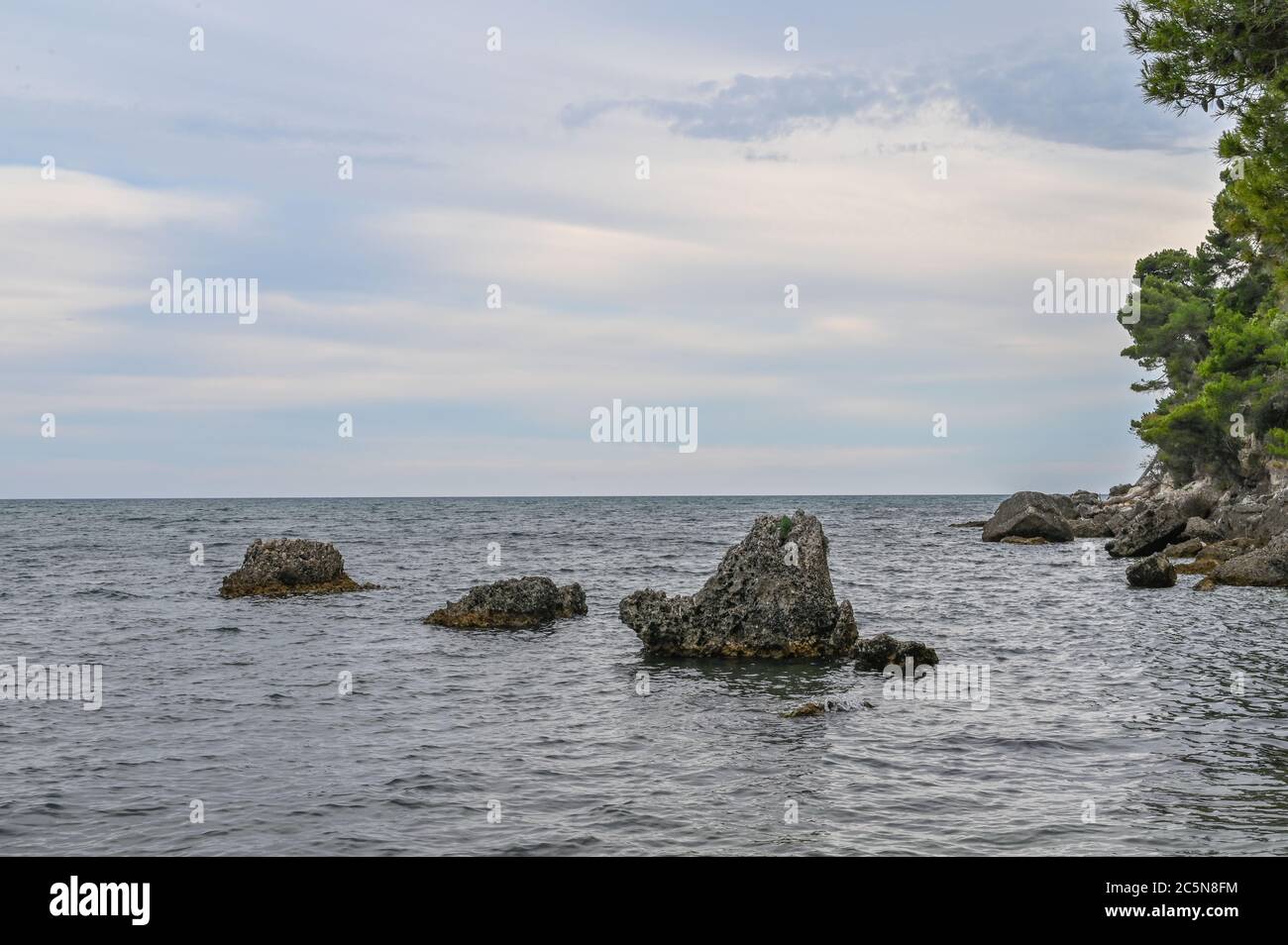 Seaside view, surrounded by rocks and trees Stock Photo - Alamy