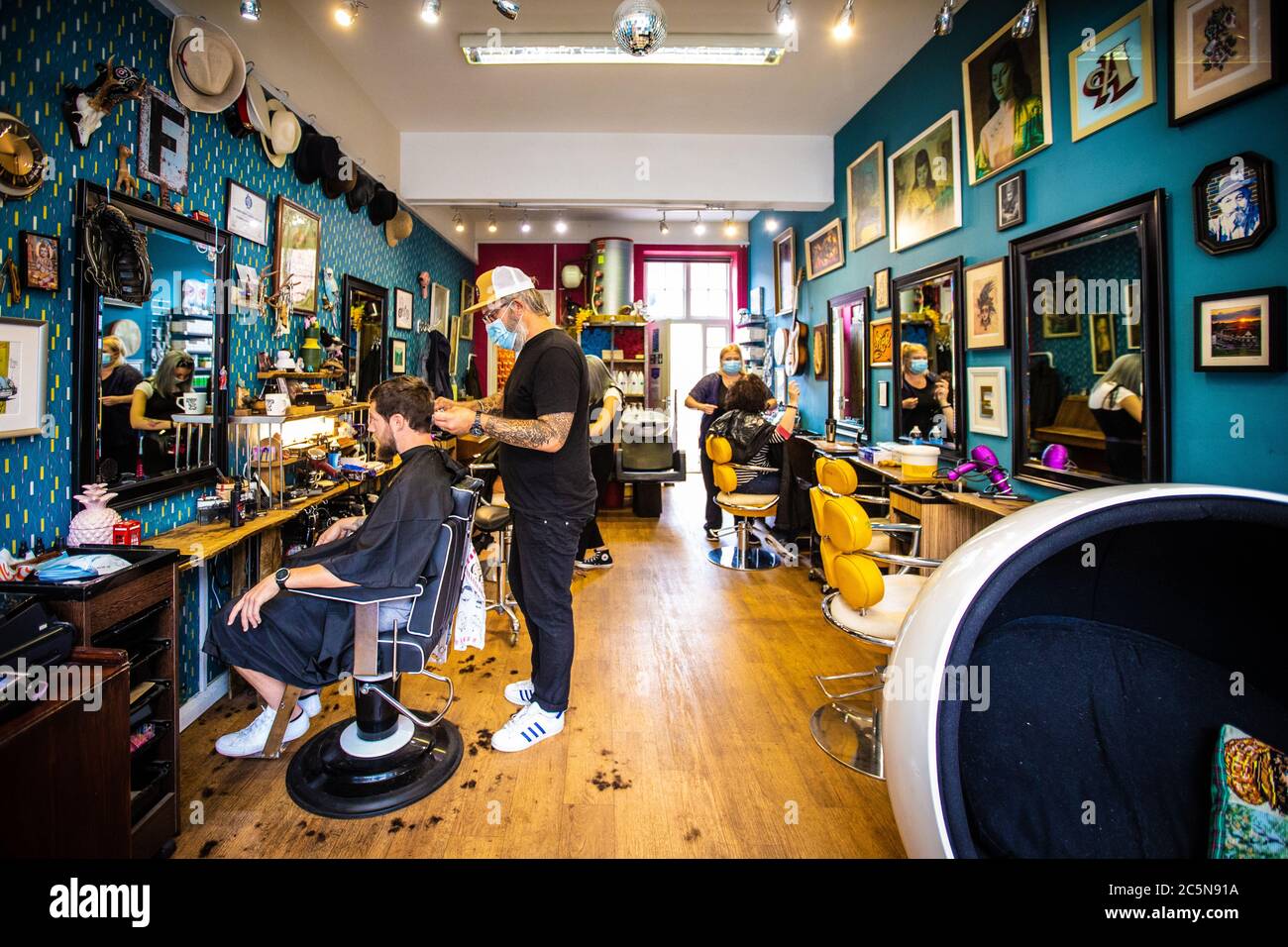 Barber cutting hair wearing PPE face mask at hair salon in early days of lockdown easing during Coronavirus pandemic. England July 2020 Stock Photo