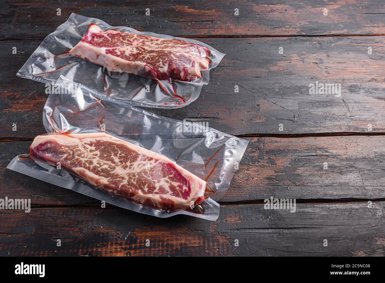 Vacuum packed meat , top blade beef steak on dark old wooden table