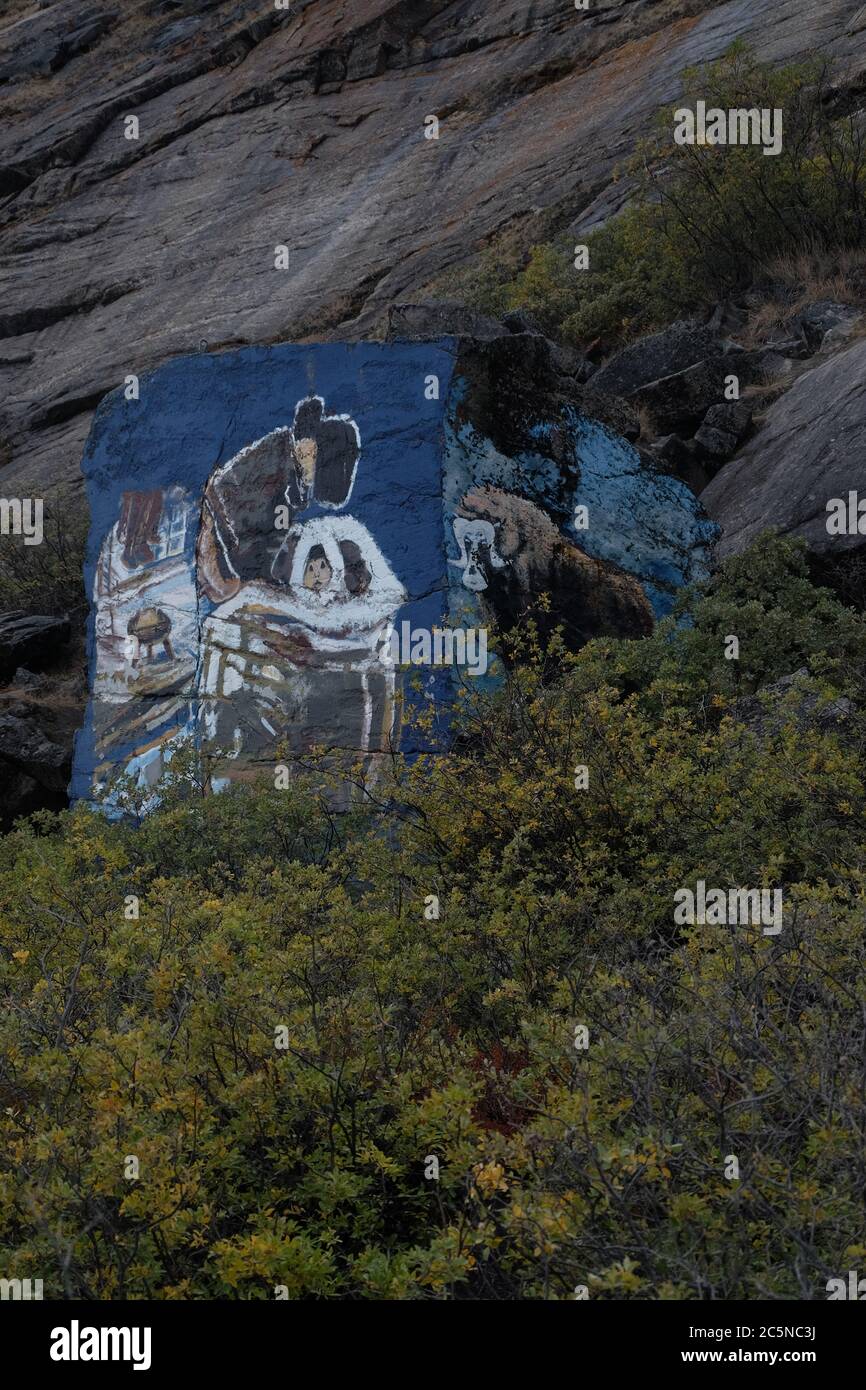 Colourful rock painting of Inuit mother and child and musk ox on a remote hillside above Kangerlussaq airfield. Stock Photo