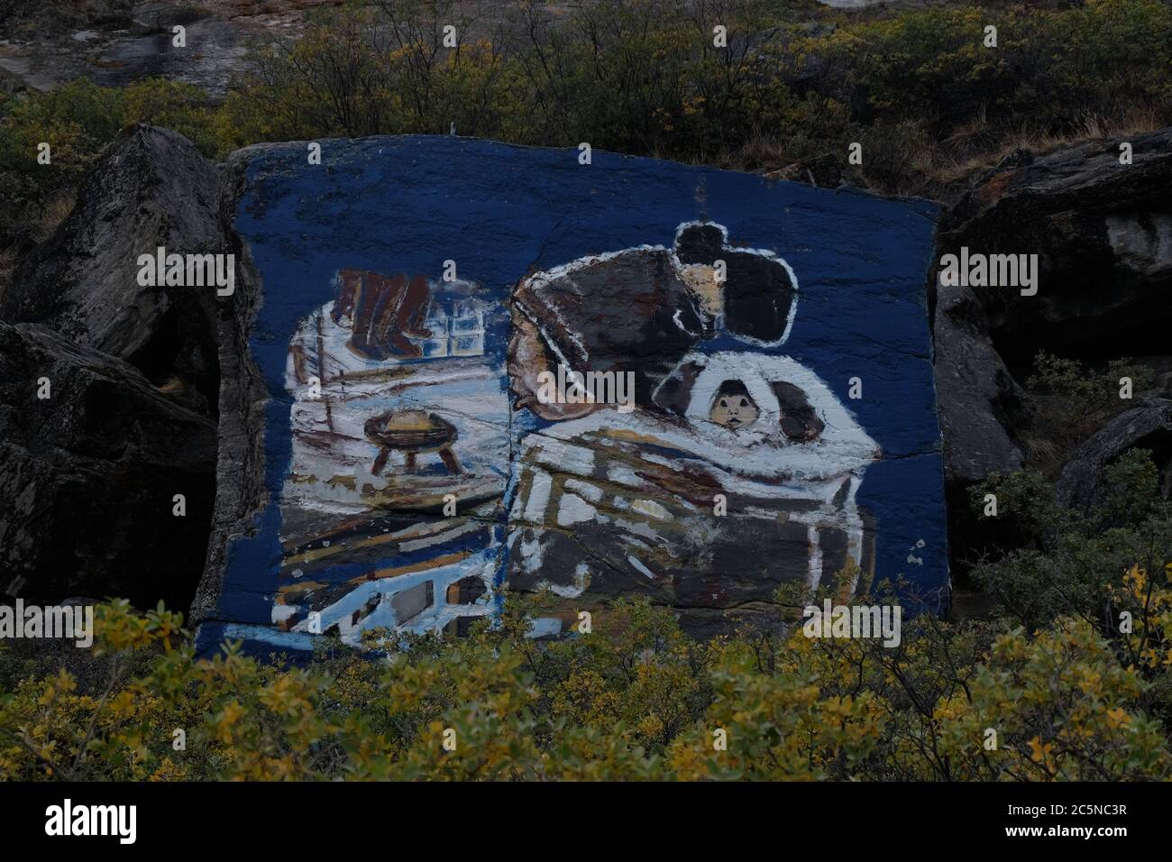 Colourful rock painting of Inuit mother and child and musk ox on a remote hillside above Kangerlussaq airfield. Stock Photo