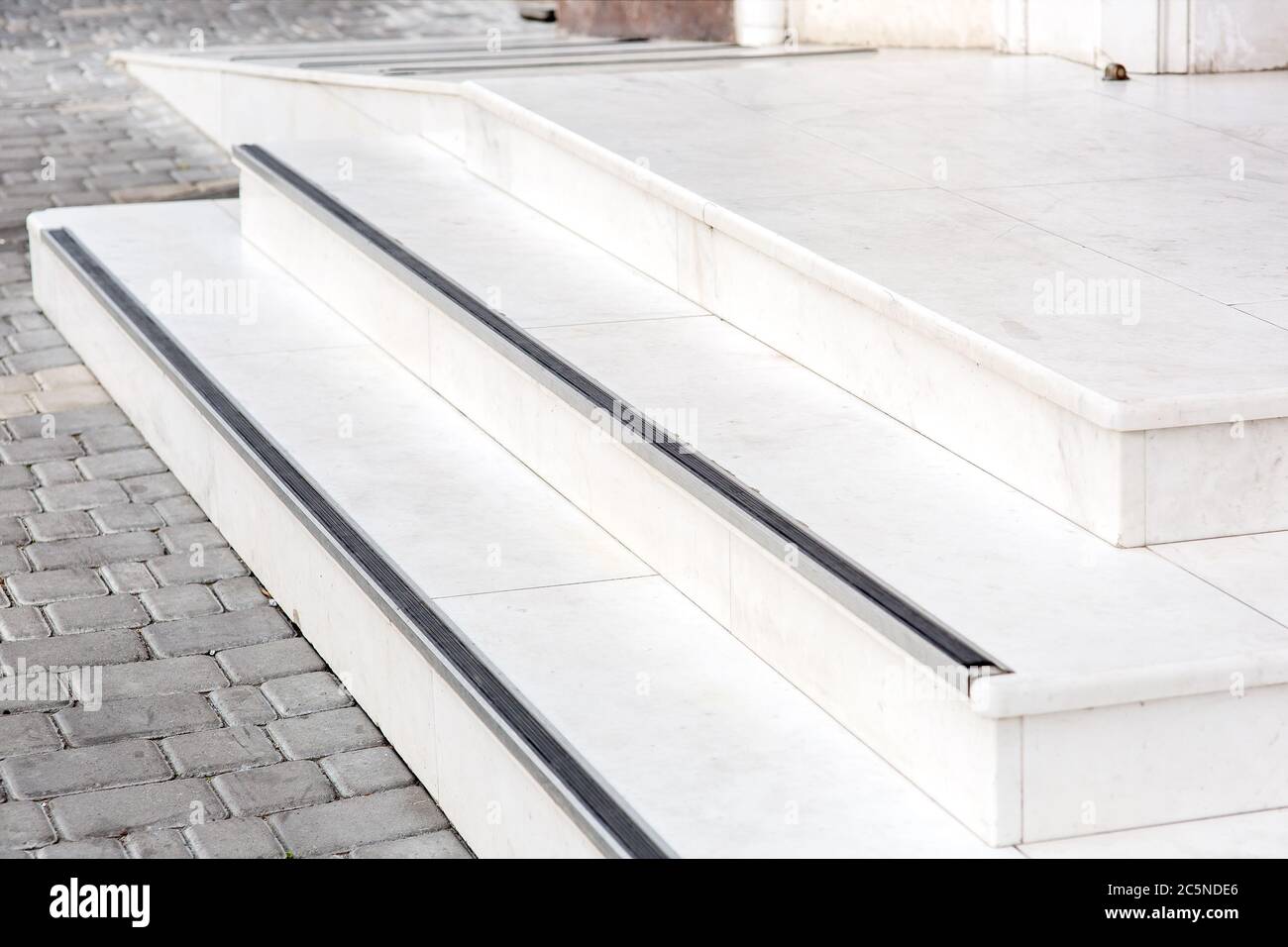 entrance with a marble threshold with stone steps and a white ramp to