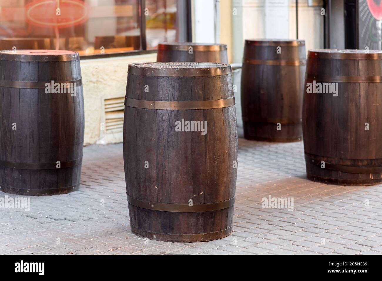 brown wooden wine barrel on the street on stone paving slabs, bar restaurant decorations close up nobody. Stock Photo