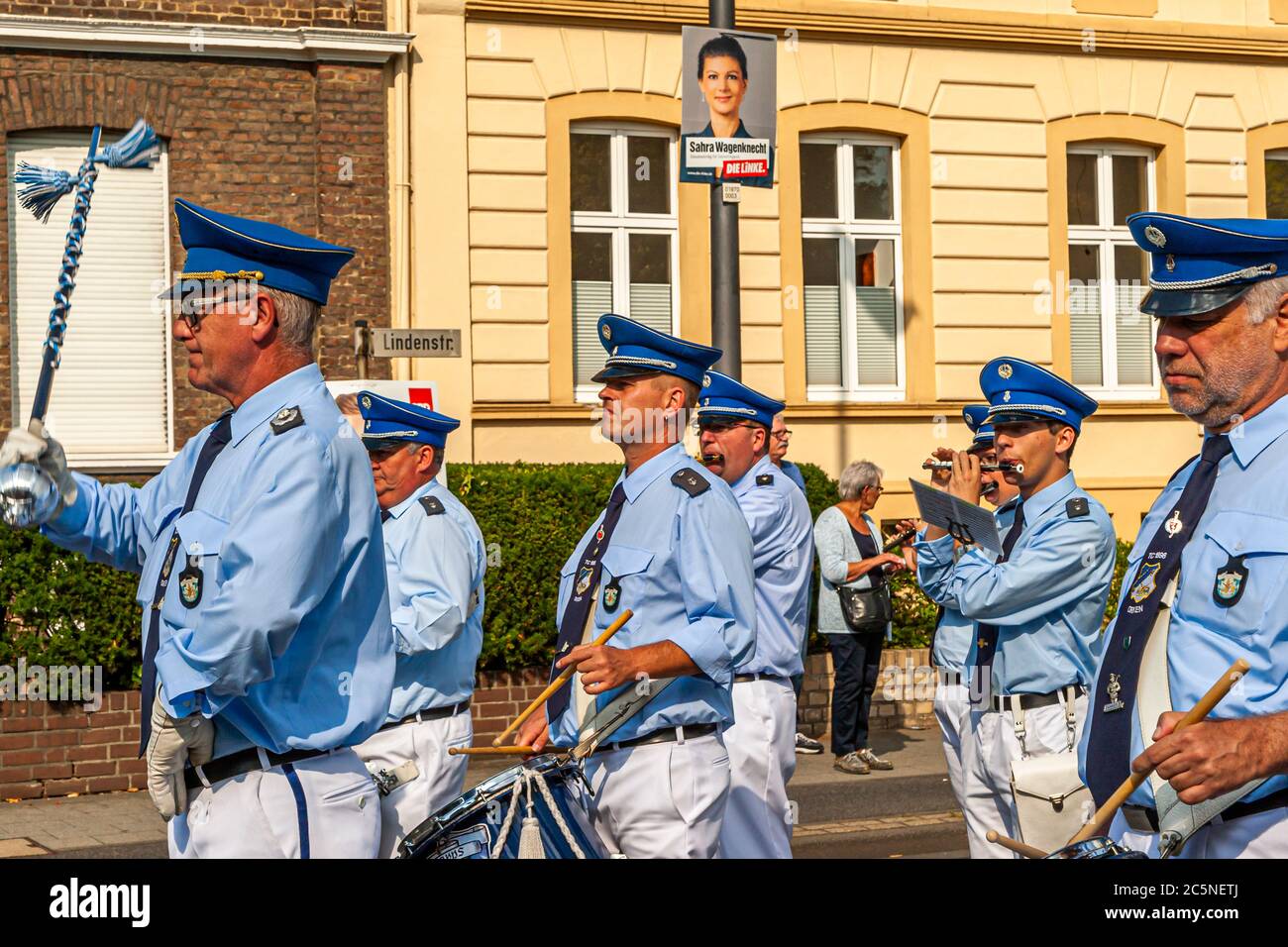 Election poster with the top candidate of the Left Party, Sahra Wagenknecht in front of which uniformed participants of a Schützenfest march by. Funfair in Grevenbroich, Germany Stock Photo