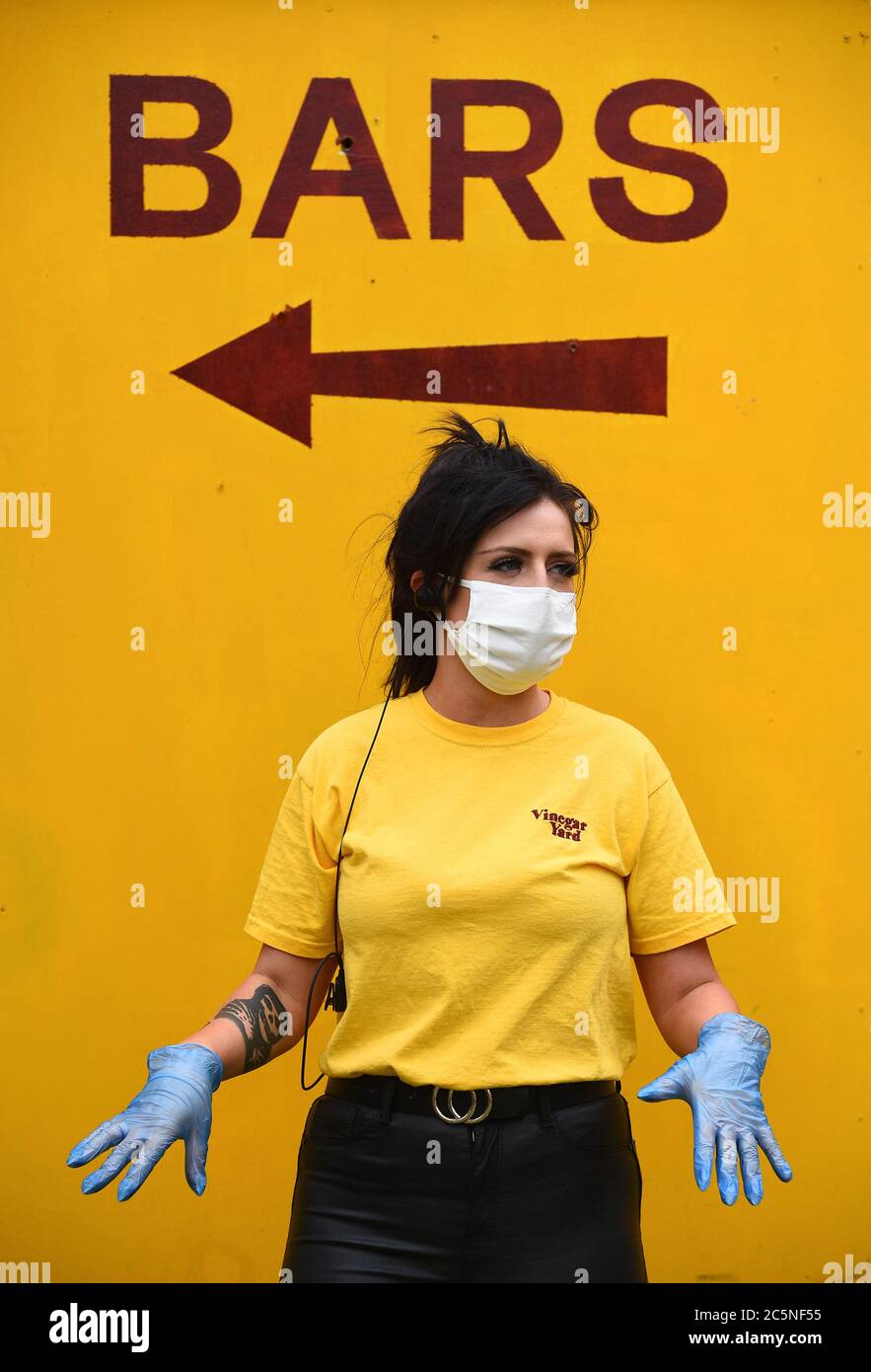 A member of staff gestures to people waiting for a table at the Vinegar Yard bar, London, as it reopens following the easing of coronavirus lockdown restrictions across England. Stock Photo
