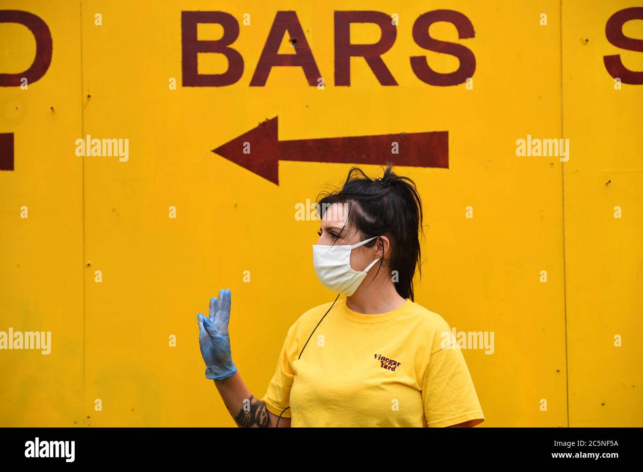 A member of staff gestures to a colleague at the Vinegar Yard bar, London, as it reopens following the easing of coronavirus lockdown restrictions across England. Stock Photo