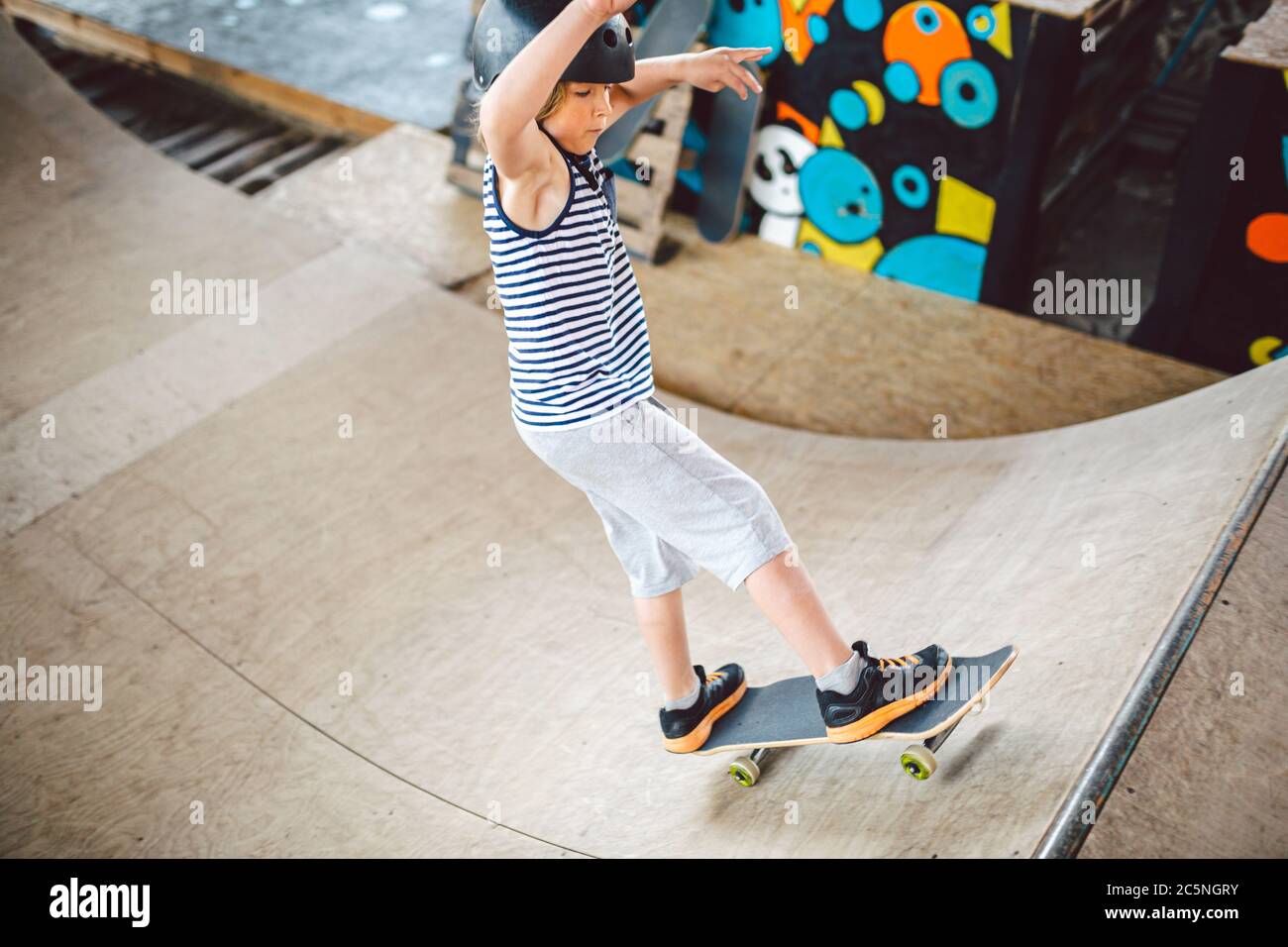 Child skateboarder during learning tricks on a ramp in an urban skate park. boy in a sports