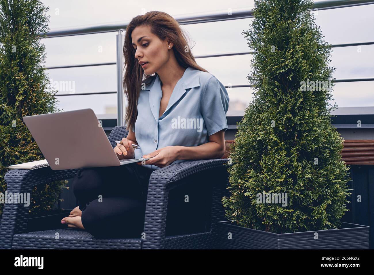 Beautiful young woman using laptop on rooftop terrace Stock Photo
