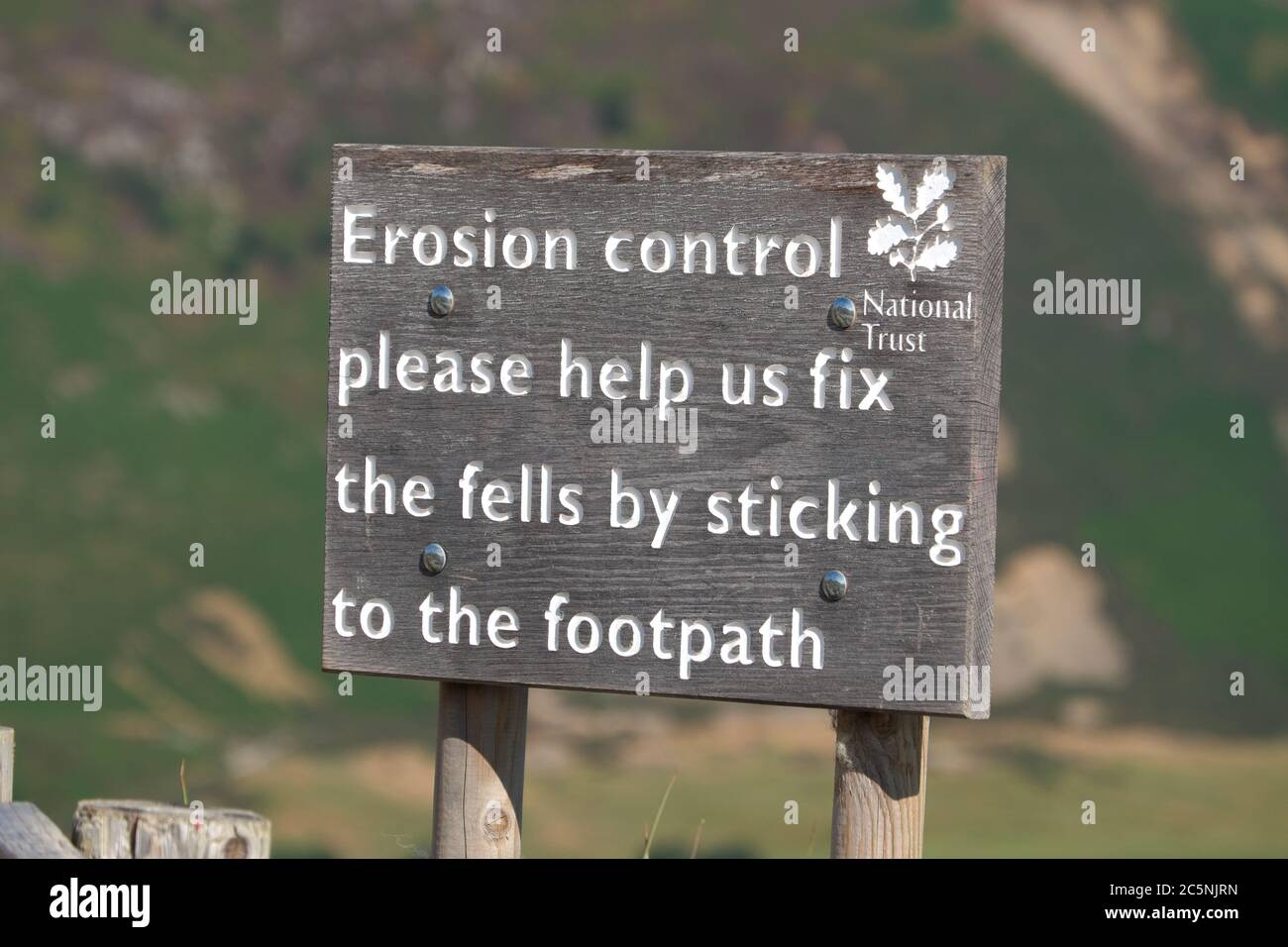 National Trust 'erosion control' sign asking walkers to keep to the path on the way up to the hugely popular summit of Cat Bells in the Lake District. Stock Photo