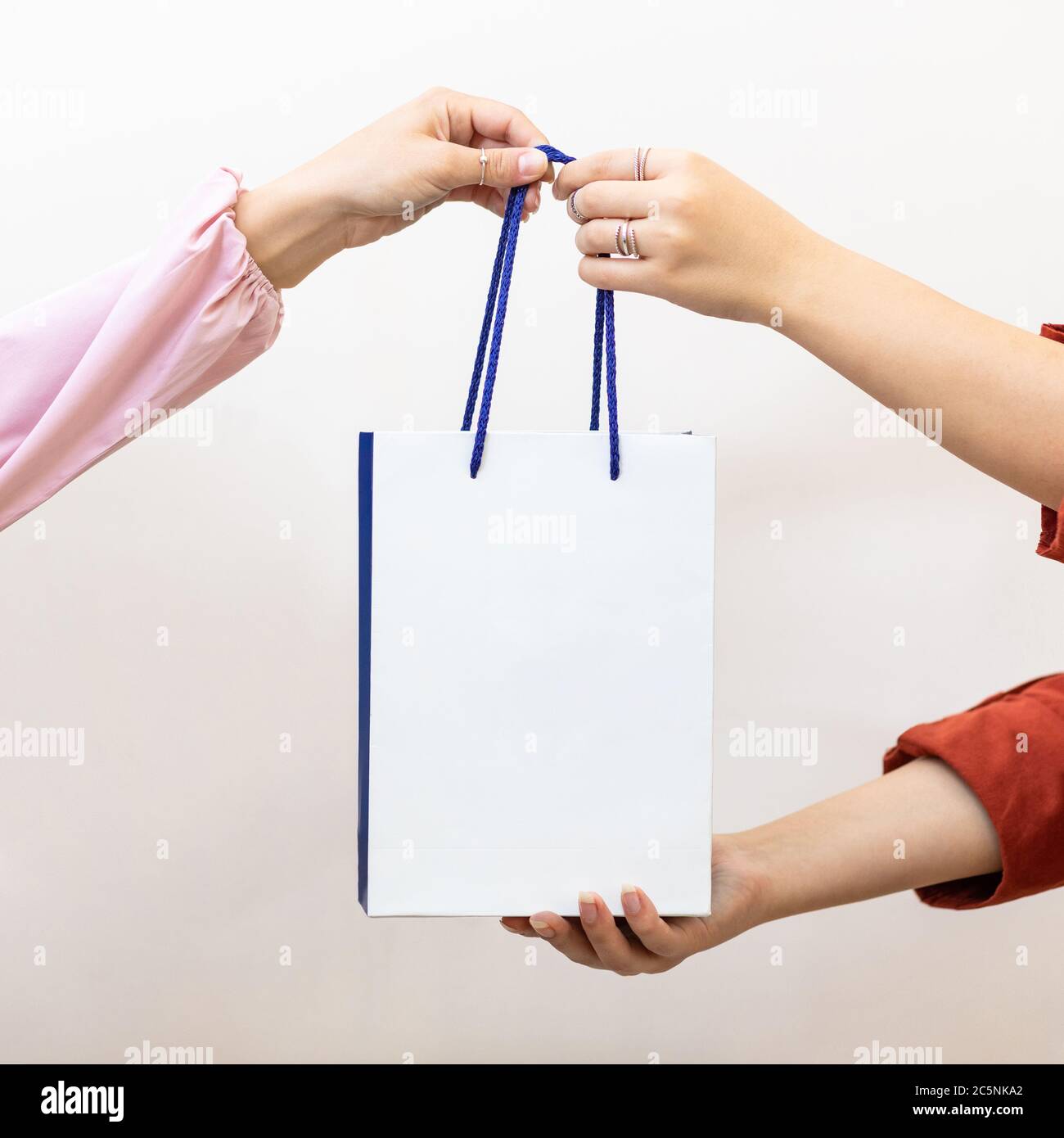 Woman giving a shopping bag to the another person Stock Photo Alamy