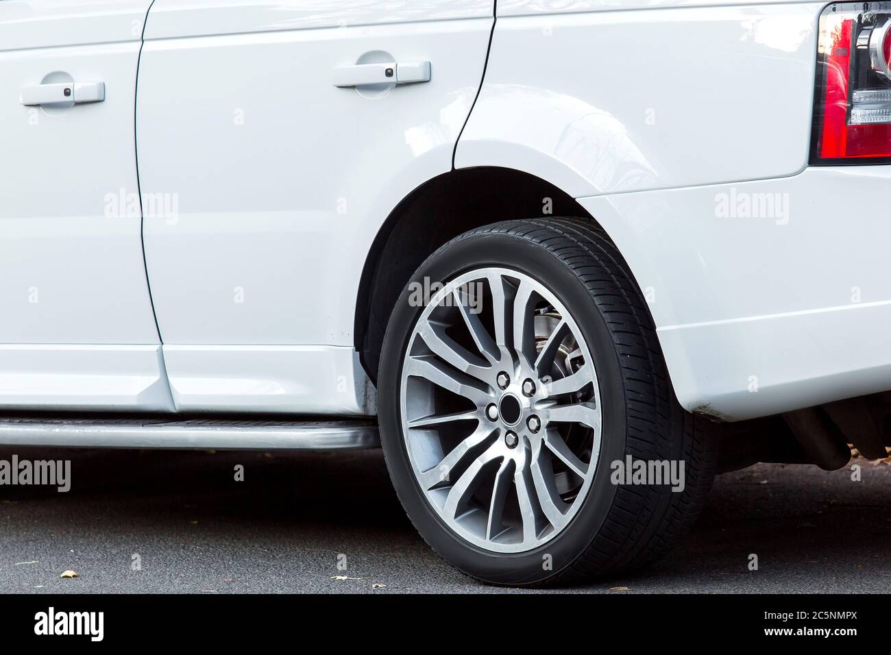 White SUV car close-up side view of the rear wheel with a wing and doors with handles, nobody. Stock Photo