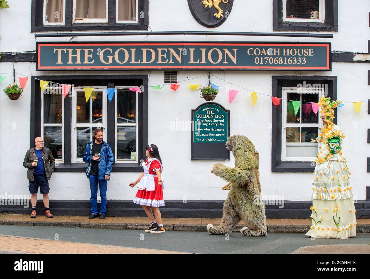 Street artists perform for costumers outside the Golden Lion pub in Todmorden, West Yorkshire, as it reopens following the easing of coronavirus lockdown restrictions across England. Stock Photo