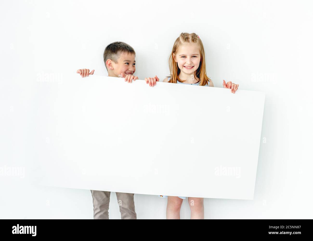 Happy boy and girl children holding big blank poster Stock Photo - Alamy