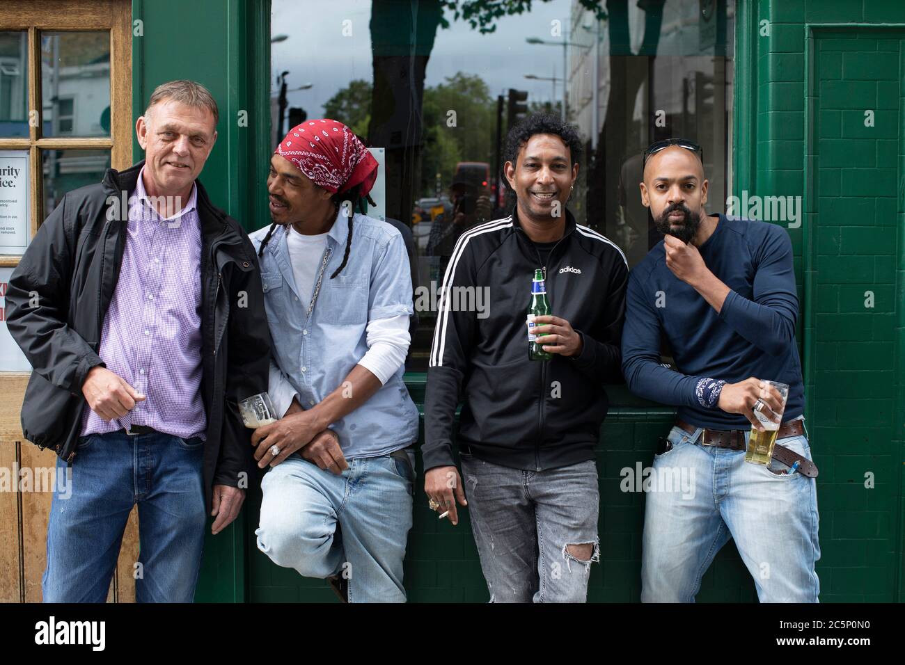 Peckham, England. 4th July 2020. Four men enjoy a drink outside their local pub, The Nags Head, in Peckahm following the British Governments announcement to ease the lockdown rules. Pubs, bars and restaurants reopen today having been closed for over three months in the UK due to the coronavirus pandemic. (photo by Sam Mellish / Alamy Live News) Stock Photo