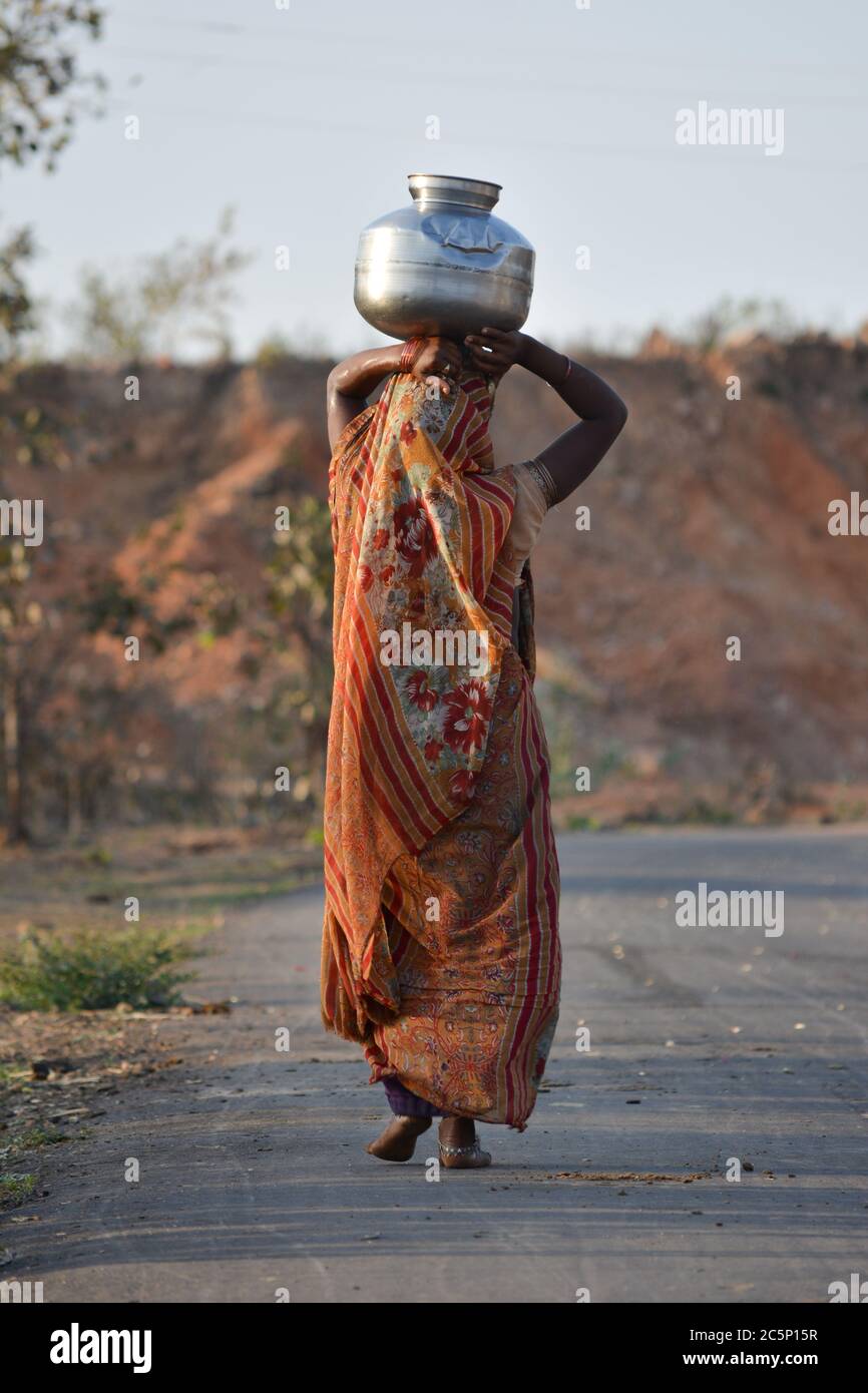 An Indian woman carrying a container of water on her head Stock Photo