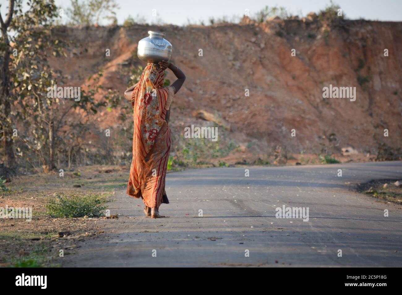 An Indian woman carrying a container of water on her head Stock Photo