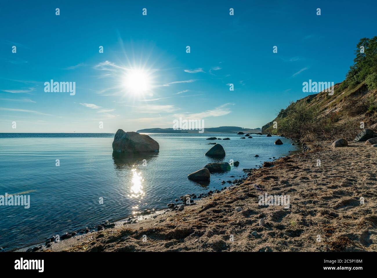 A sunstar over some rocks at the beach of Klein Zicker on the german island Ruegen Stock Photo