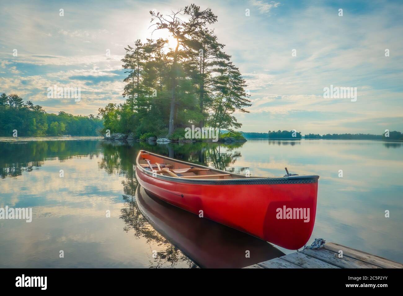 Canoe tied to a dock on the calm waters of Stony Lake in the early morning when it is calm and serene, Stock Photo