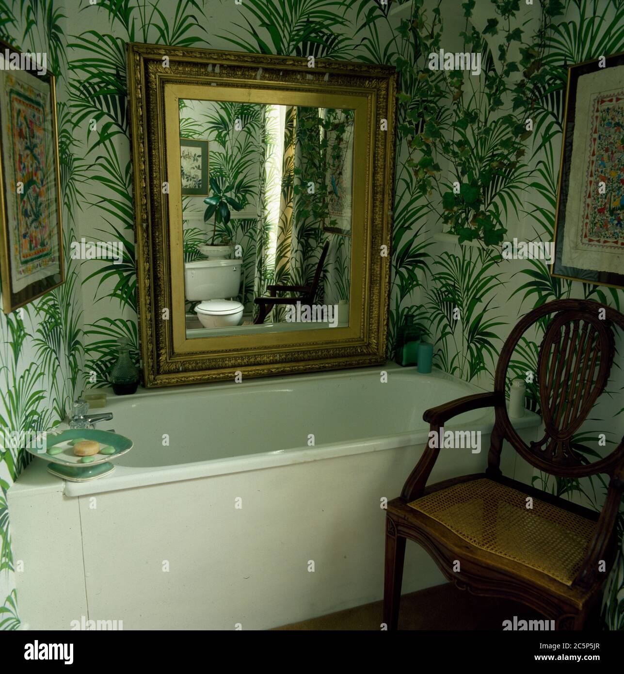 Cottage bathroom with large gilt mirror on botanic wallpaper Stock Photo