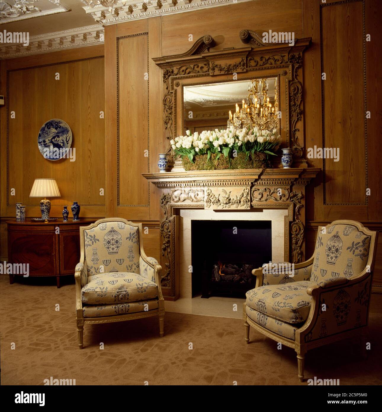 Wood panelled room with two formal armchairs in front of traditional