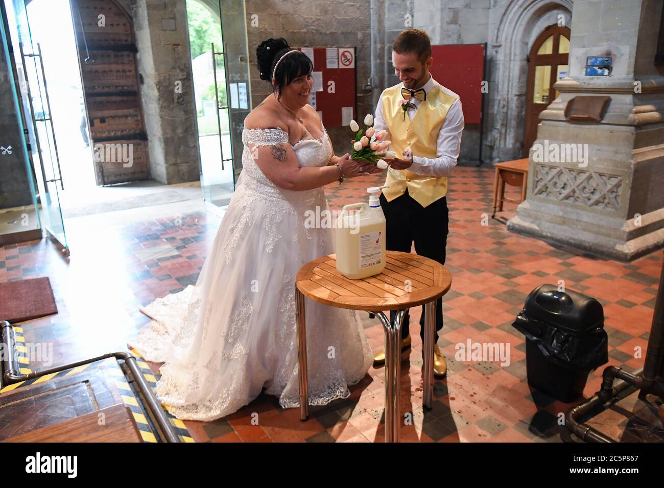 Bride Tina-Lynn Birch uses hand sanitiser before entering the Priory Church of St Peter, Dunstable, Bedfordshire, as weddings are once again permitted to take place in England, with ceremonies capped at a maximum of 30 guests. Stock Photo