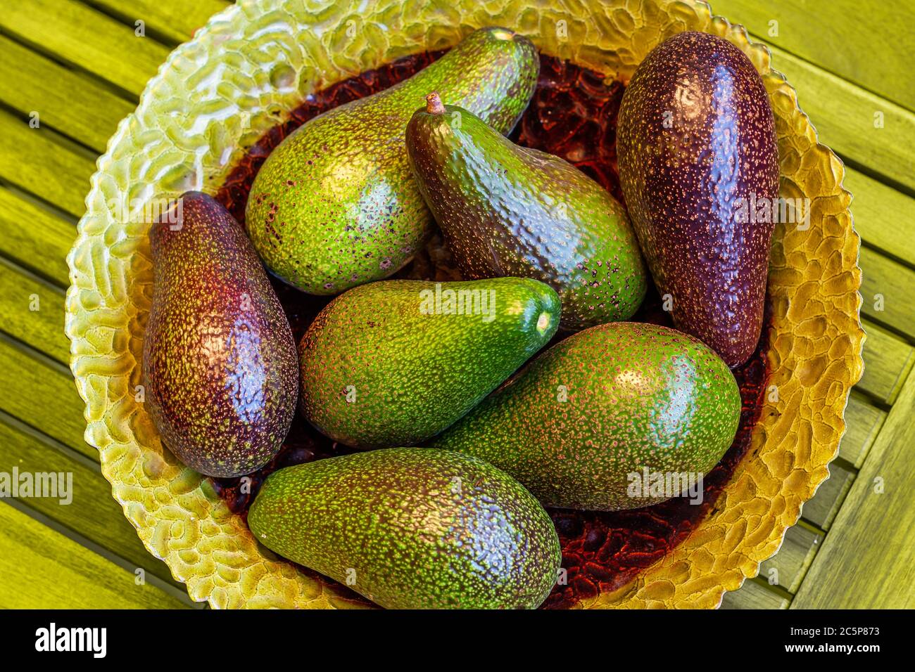 Ripe organic avocados in green plate on wooden background. Healthy eating stile life concept. Detox food. Top view Stock Photo