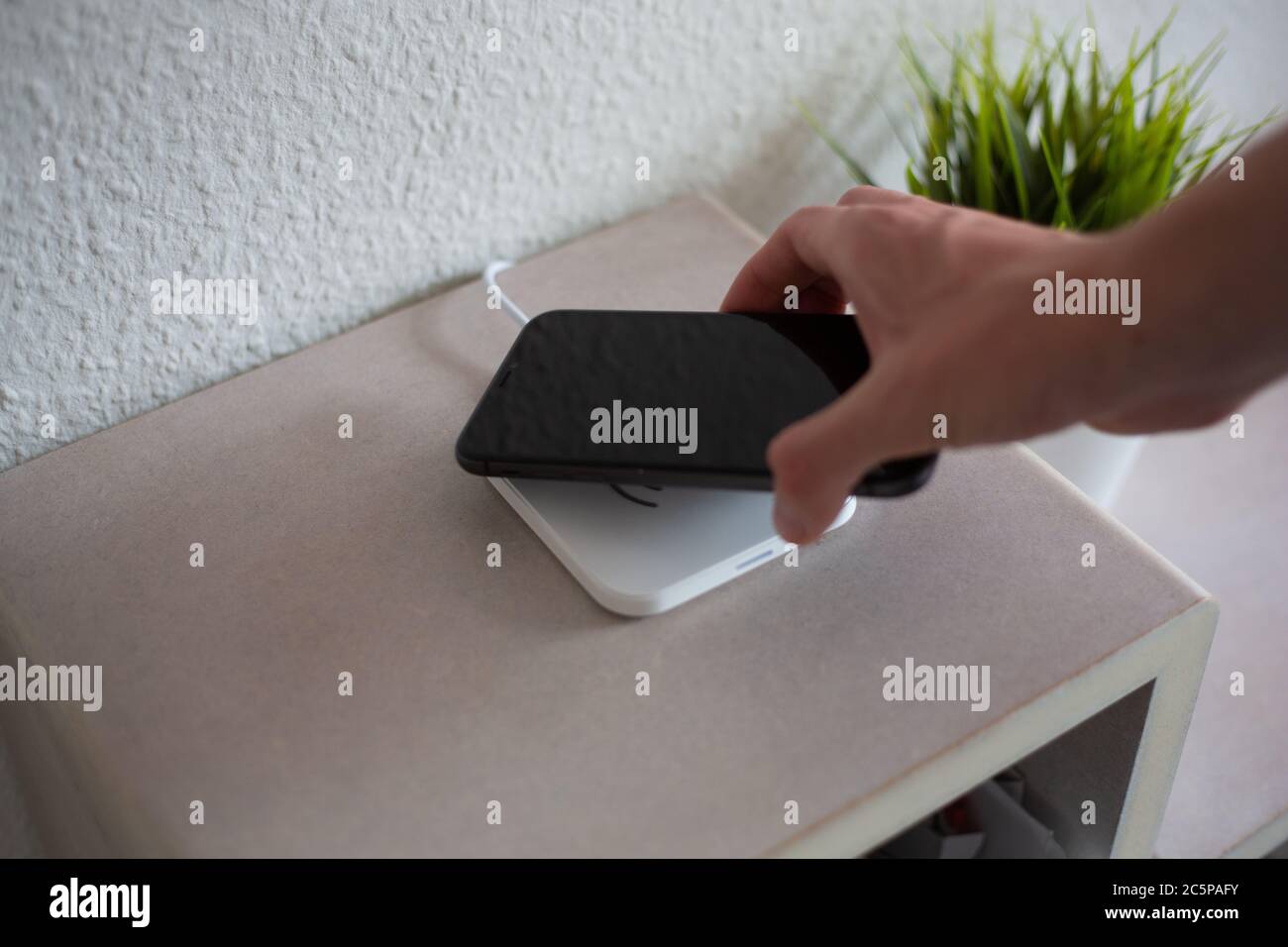 Smartphone being placed on wireless charging pad to charge battery Stock Photo