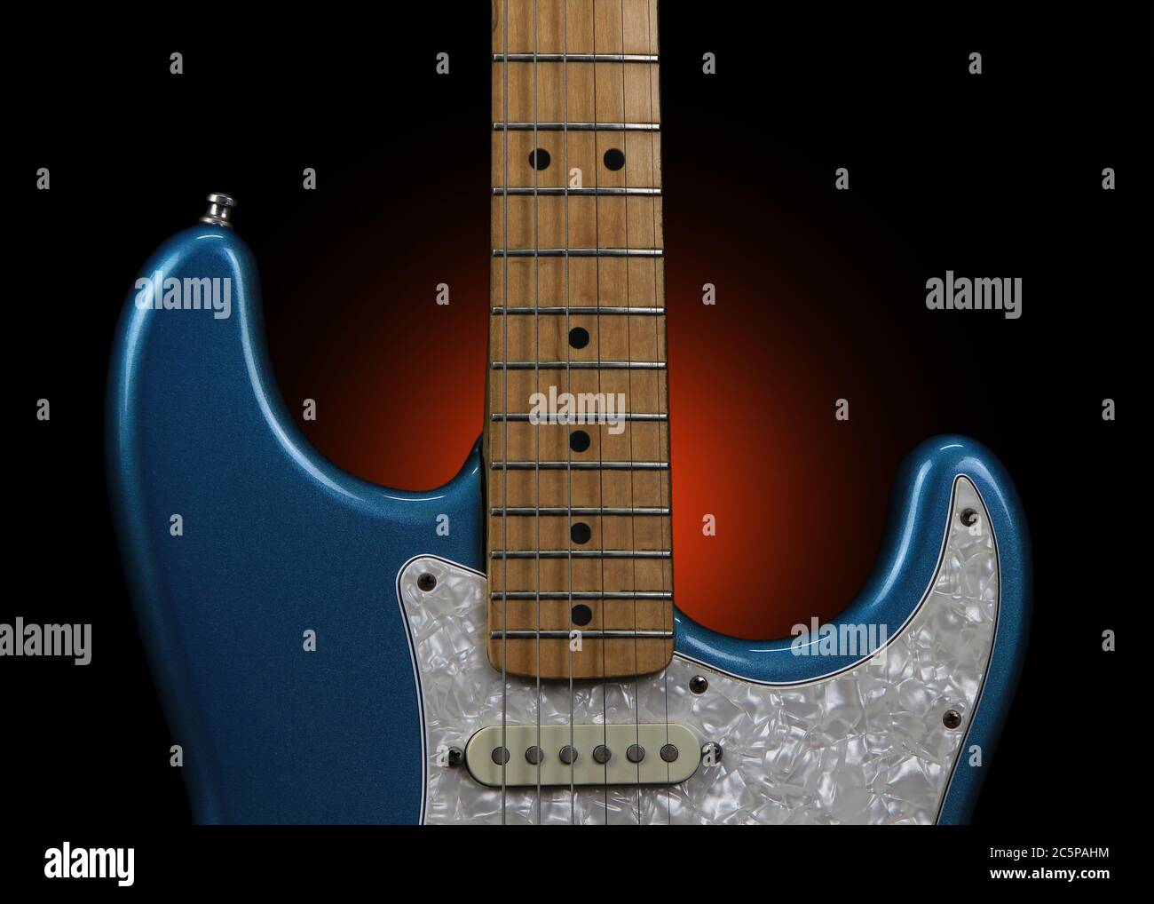 Detail of a Fender Stratocaster electric guitar in Blue Sparkle showing the cutouts, fingerboard and frets, one single-coil pickup, and the top of the white pearl pickguard. Stock Photo