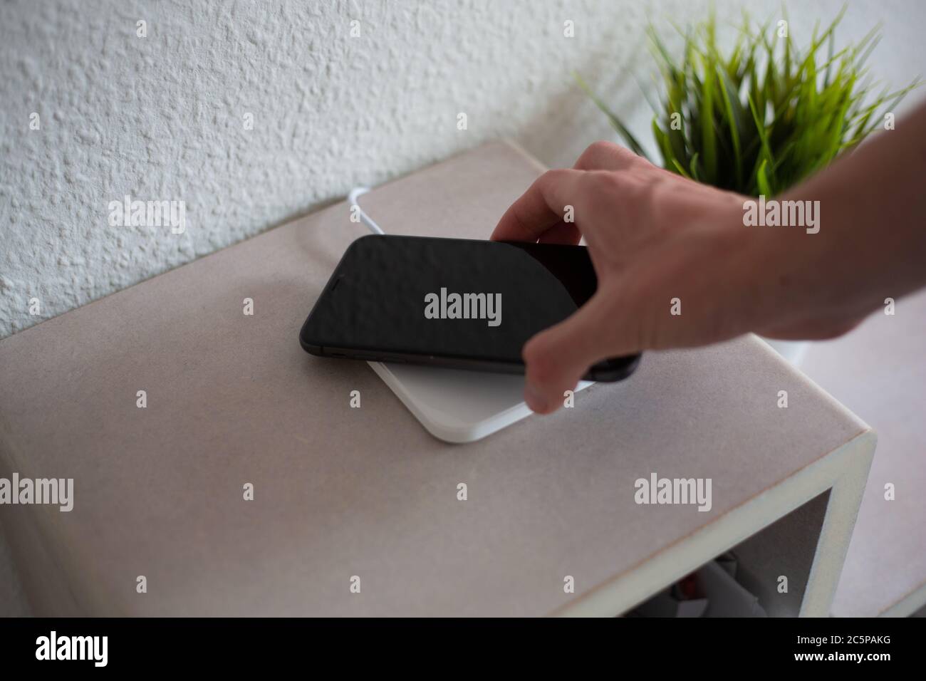 Smartphone being placed on wireless charging pad to charge battery Stock Photo