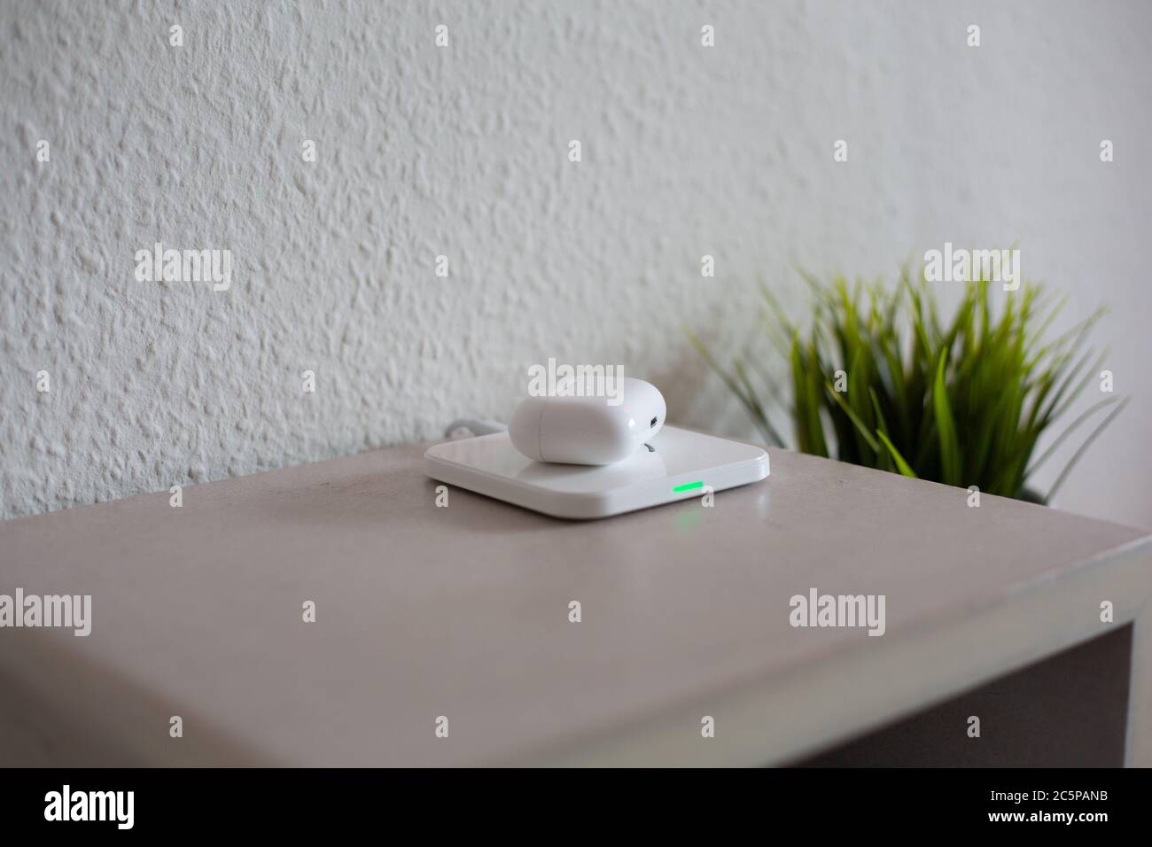 Wireless Headphones being placed on wireless charging pad to charge battery Stock Photo