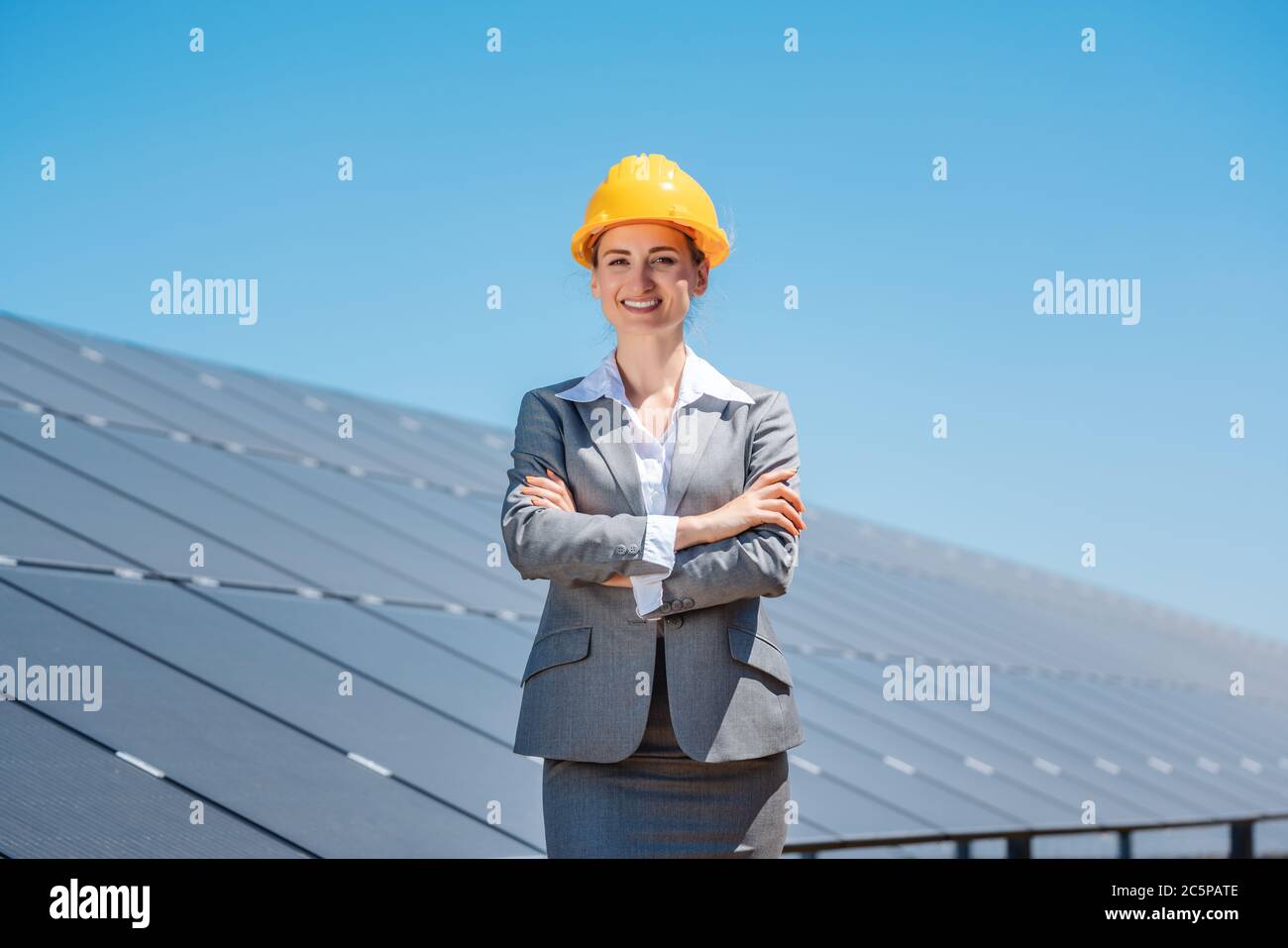 Woman investor in clean energy standing in front of solar panels Stock Photo