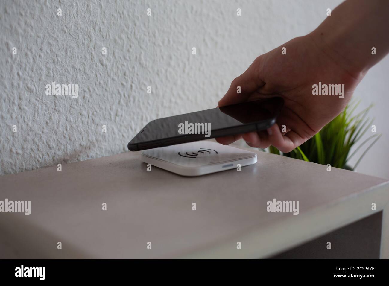Smartphone being placed on wireless charging pad to charge Stock Photo