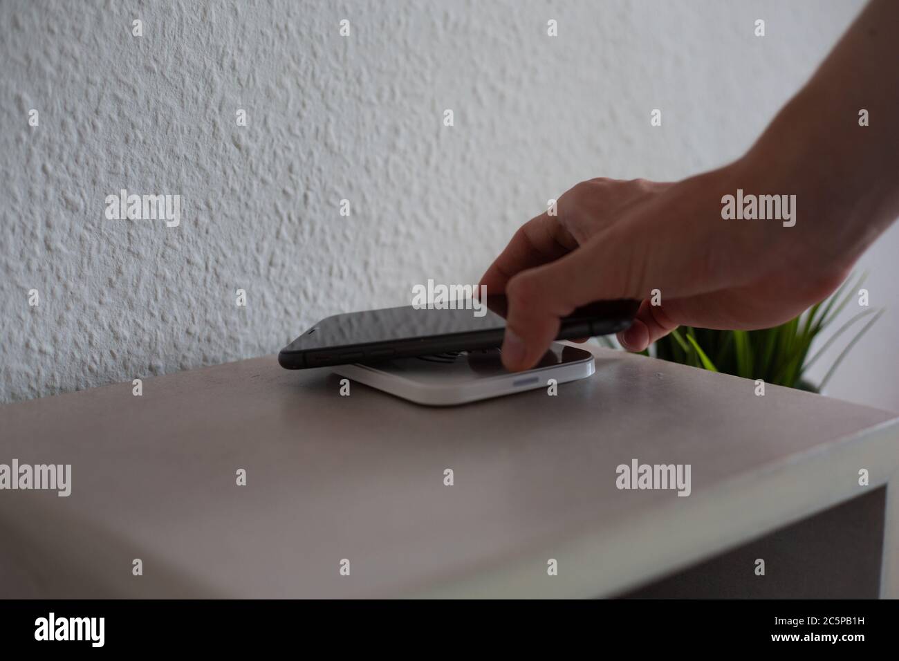 Smartphone being placed on wireless charging pad to charge battery Stock Photo