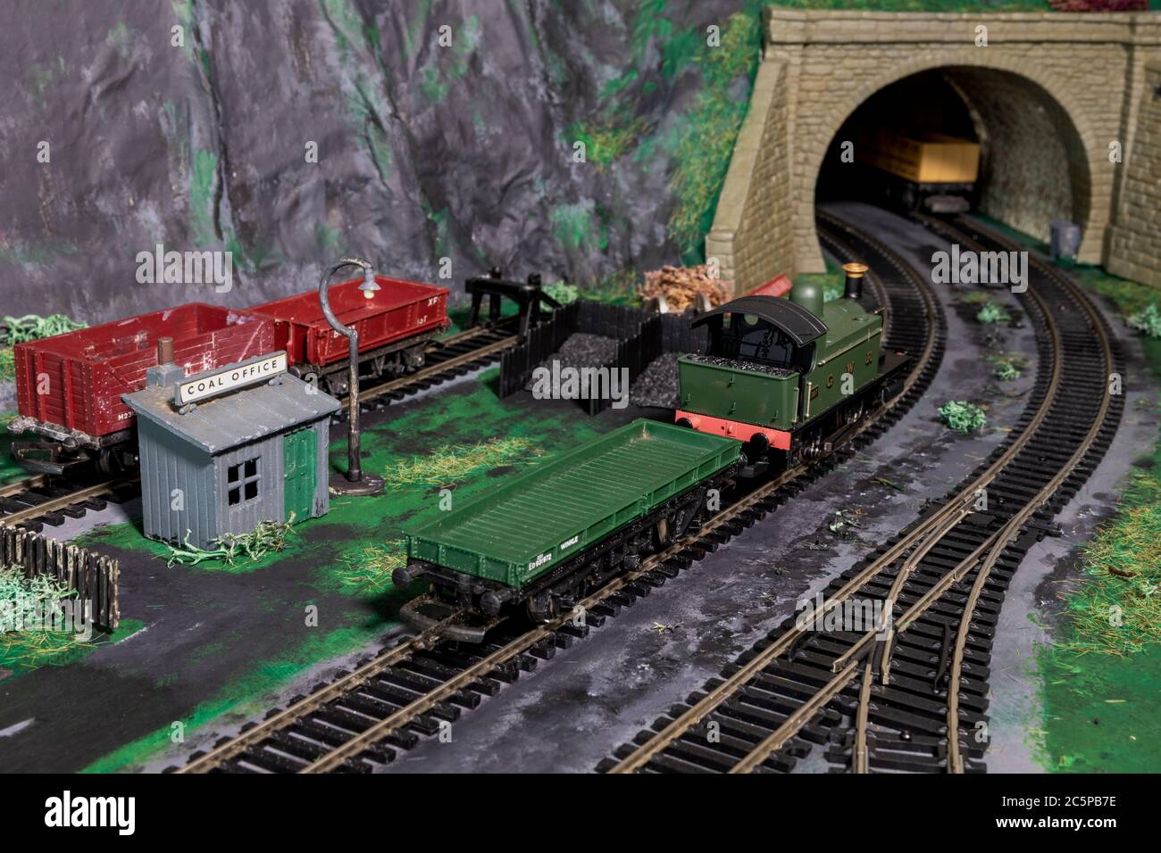 H0 00 Scale coal station on a model railway. GWR Tank Engine passing by on the main line with trucks in a siding. Stock Photo