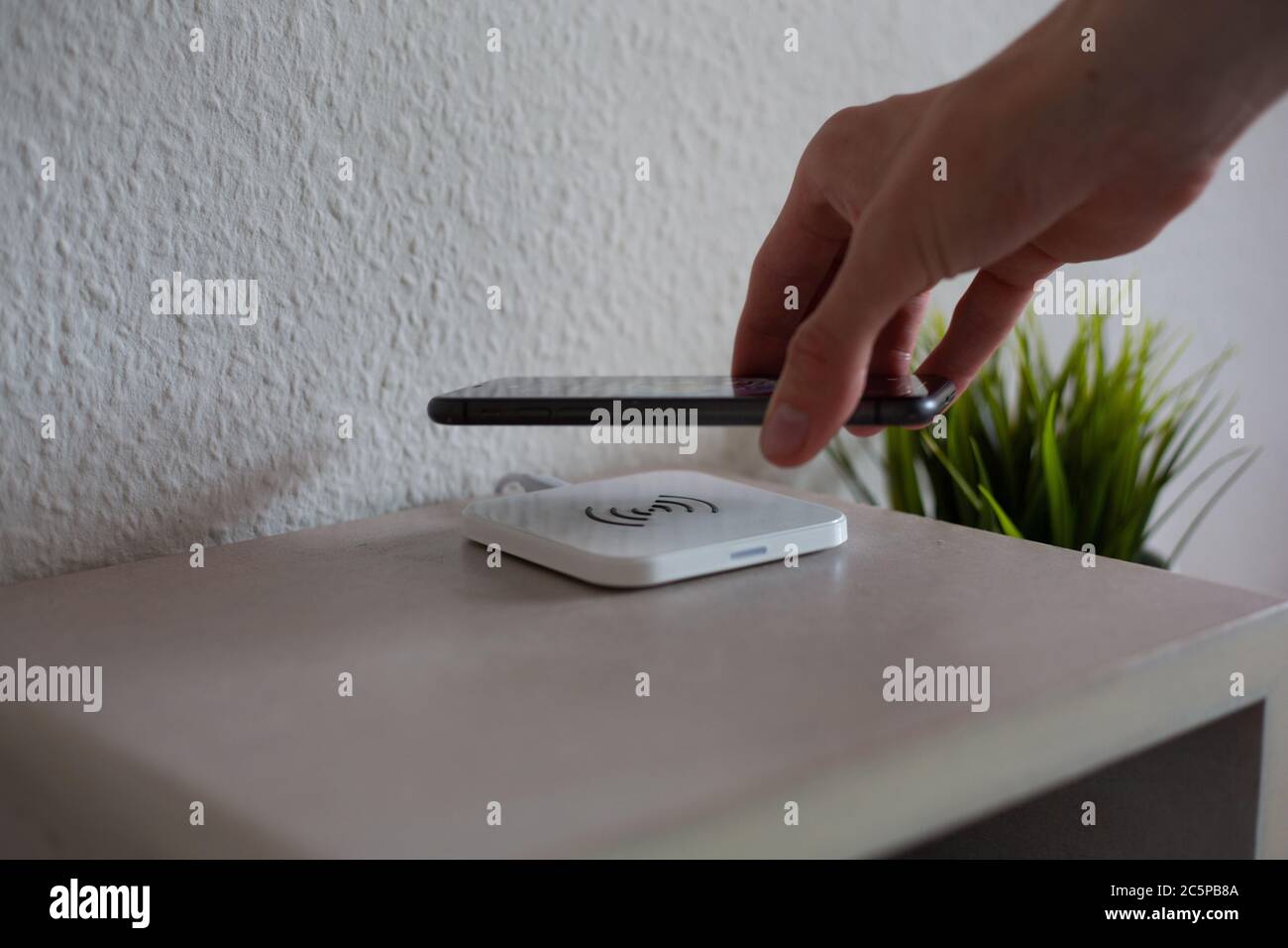 Smartphone being placed on wireless charging pad to charge battery Stock Photo